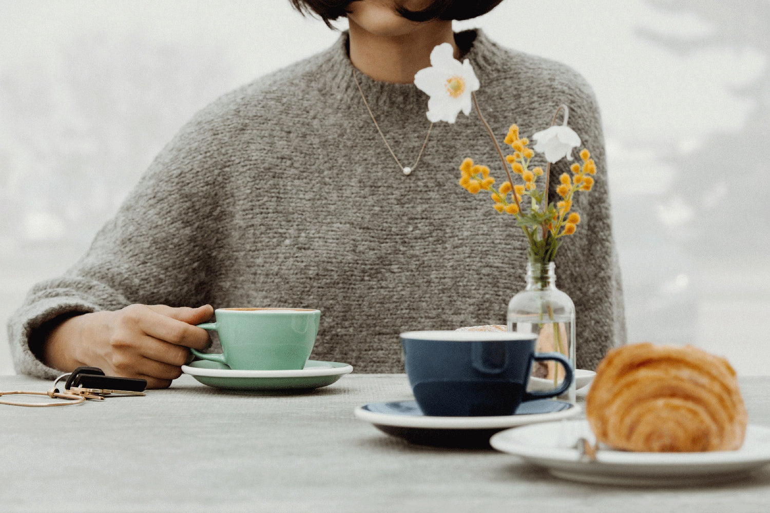 Woman with grey sweater holding a Feijoa Acme cappuccino cup