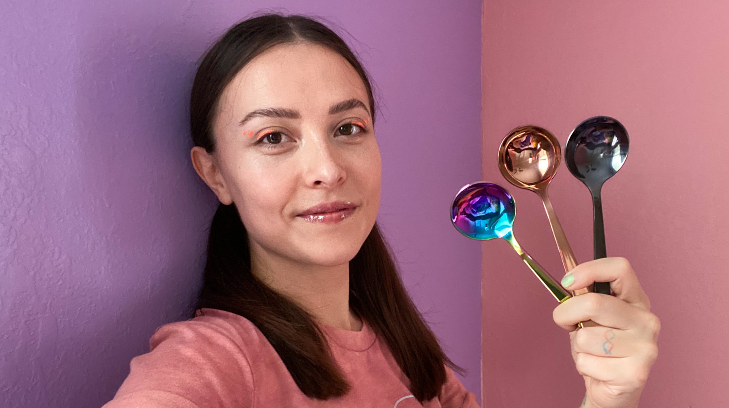 Umeko Motoyoshi holding three Umeshiso cupping spoons against a lilac and pink background